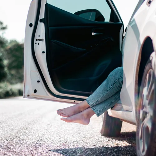 Woman getting out of her car to a clean driveway.